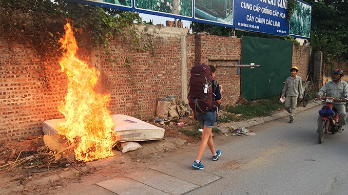 Frau mit Vaude AStrum Rucksack läuft an einem Feuer vorbei